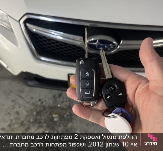 מפתחות רכב מול מכונית לבנה עם סמל סובארו